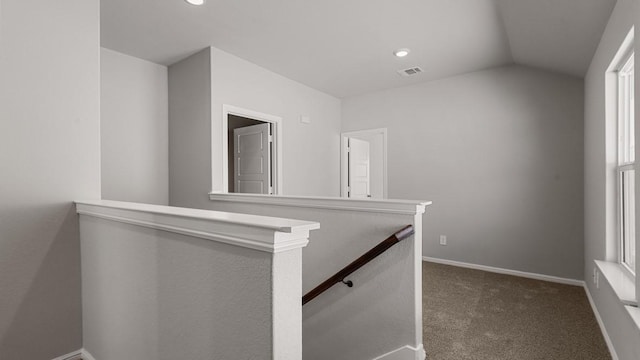 hall with dark carpet and lofted ceiling