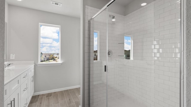 bathroom featuring a shower with door and vanity