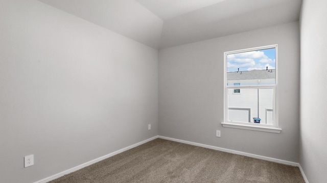 carpeted spare room featuring vaulted ceiling