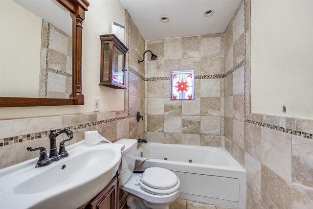 full bathroom with toilet, vanity, tile walls, and tiled shower / bath