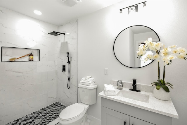 bathroom featuring vanity, toilet, and tiled shower