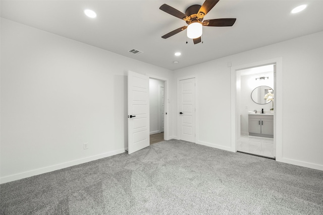 unfurnished bedroom featuring sink, ensuite bath, carpet floors, and ceiling fan