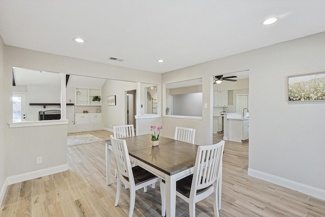 dining area featuring sink, ceiling fan, built in features, and light hardwood / wood-style flooring