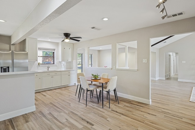 dining area with ceiling fan, light wood-type flooring, vaulted ceiling, and sink