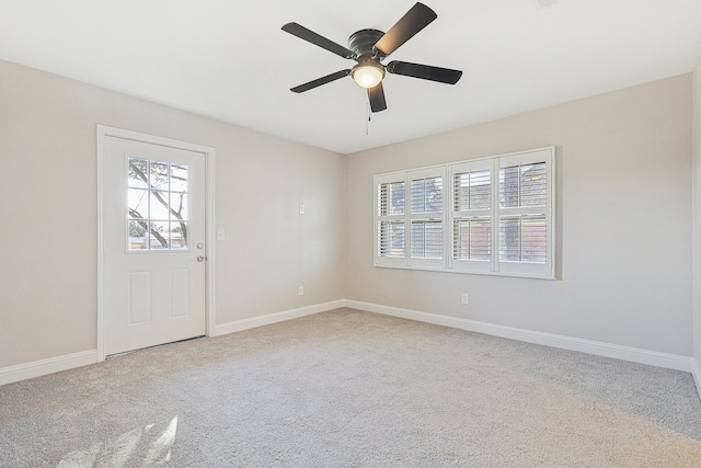 unfurnished room featuring ceiling fan, a wealth of natural light, and light carpet