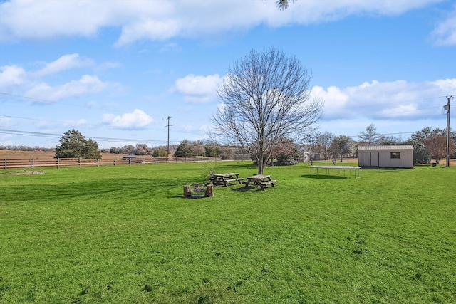 view of yard featuring an outbuilding, a rural view, and a trampoline