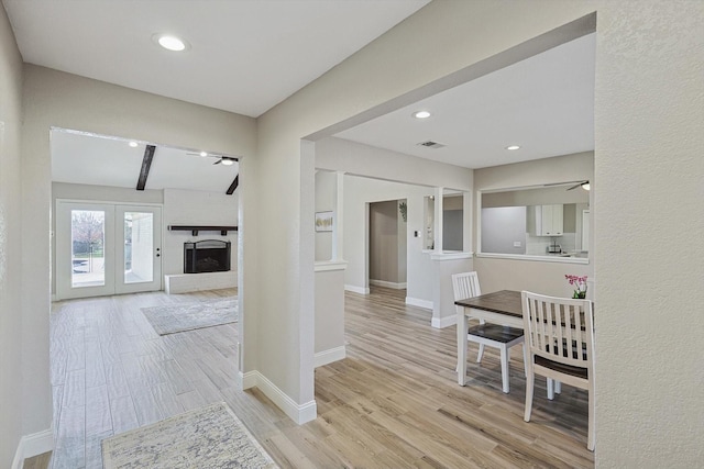 corridor featuring light wood-type flooring, french doors, and beamed ceiling