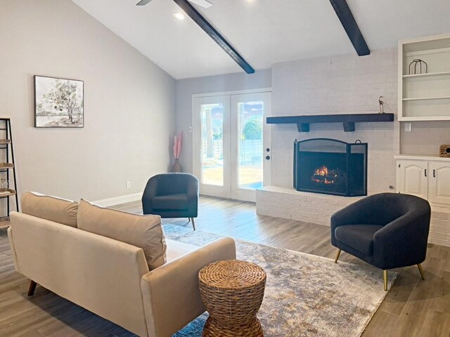 living room featuring light wood-type flooring, lofted ceiling with beams, ceiling fan, french doors, and a fireplace