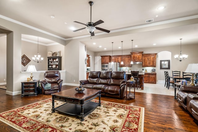 living room with dark hardwood / wood-style flooring, ceiling fan with notable chandelier, and ornamental molding