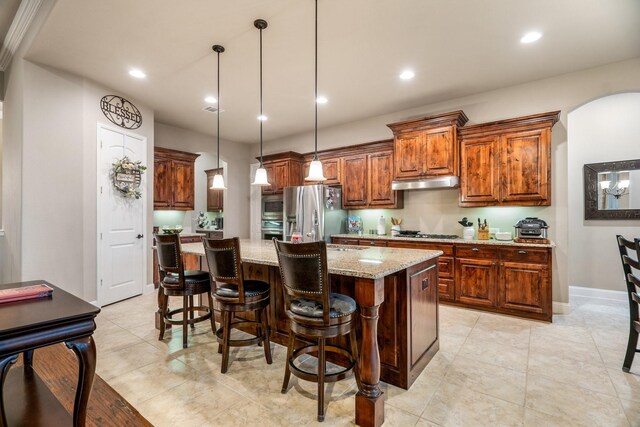 kitchen with a kitchen bar, light stone counters, stainless steel appliances, pendant lighting, and a center island