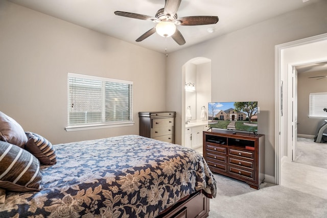 bedroom with ceiling fan, light carpet, connected bathroom, and multiple windows