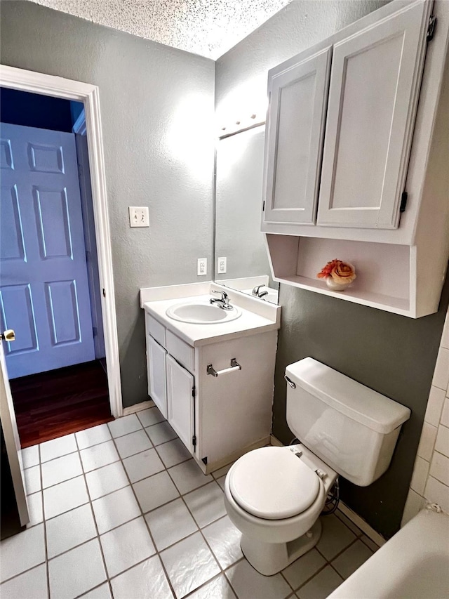 bathroom featuring toilet, vanity, tile patterned floors, and a textured ceiling