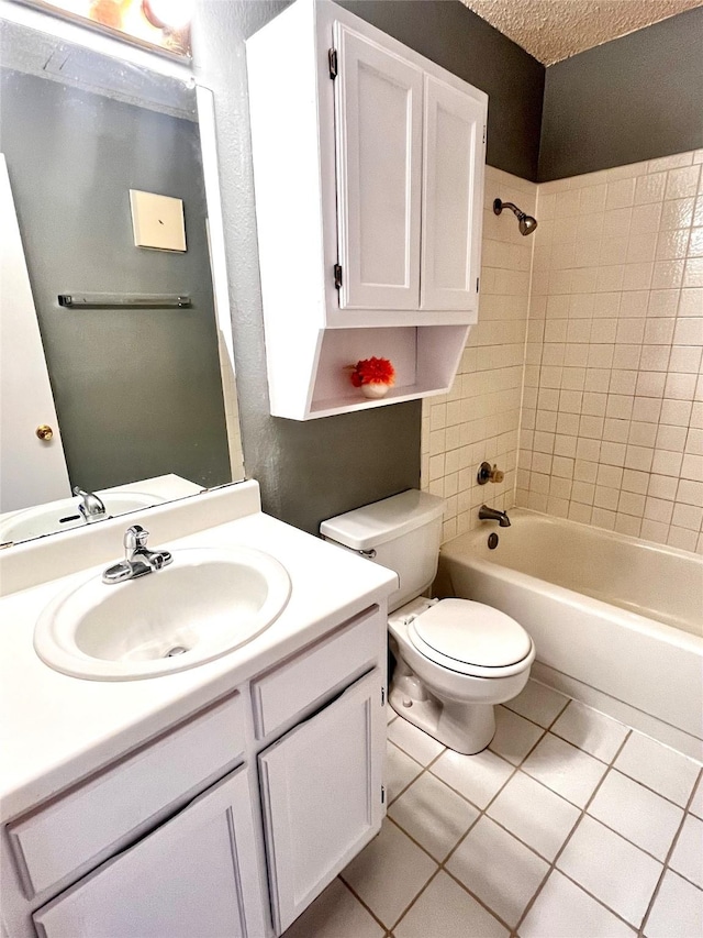 full bathroom featuring tile patterned flooring, toilet, vanity, tiled shower / bath, and a textured ceiling