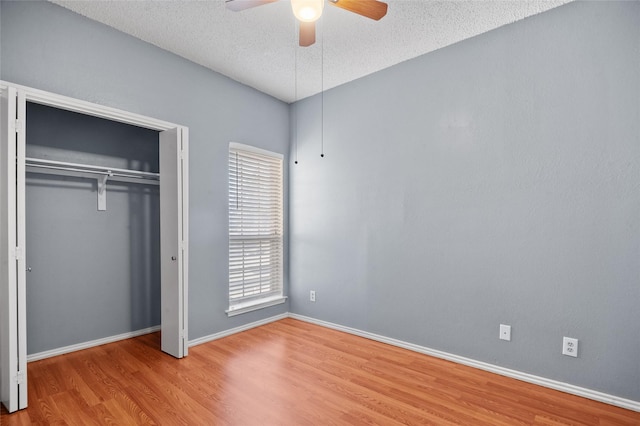 unfurnished bedroom with ceiling fan, light hardwood / wood-style floors, a closet, and a textured ceiling