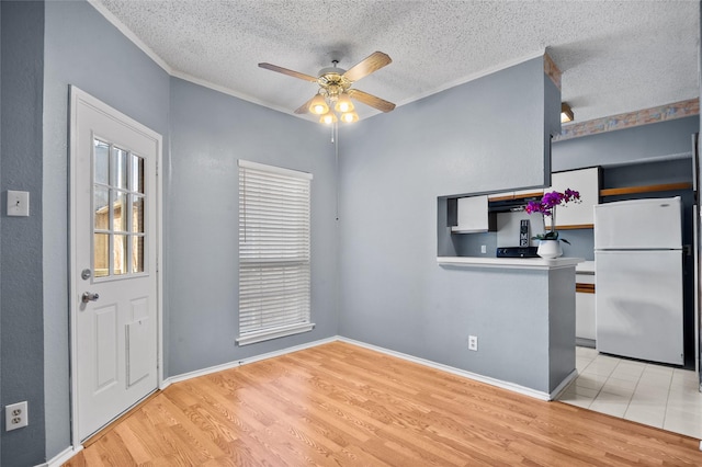 kitchen featuring white refrigerator, a textured ceiling, ceiling fan, and light hardwood / wood-style floors