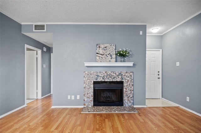 unfurnished living room featuring a tiled fireplace, hardwood / wood-style floors, crown molding, and a textured ceiling