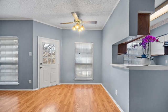 foyer entrance with a textured ceiling, ceiling fan, light hardwood / wood-style flooring, and crown molding