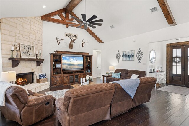 living room with beam ceiling, dark hardwood / wood-style flooring, a stone fireplace, and ceiling fan