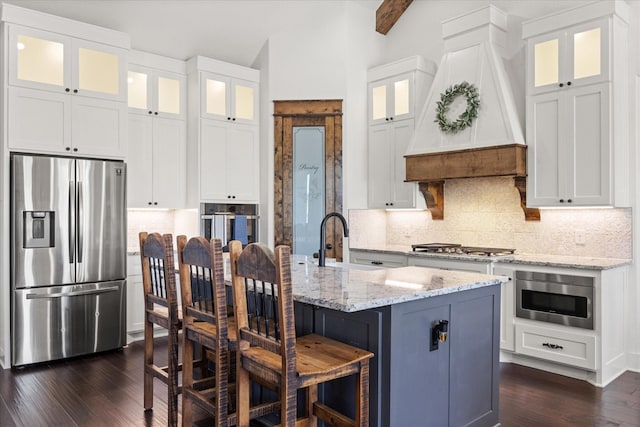 kitchen with sink, stainless steel appliances, white cabinetry, and an island with sink