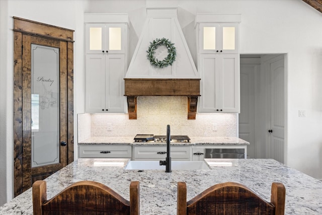 708 Glade Park Ct, Azle, TX 76020 - kitchen with stainless steel gas cooktop, a center island with sink, a sink, a notable chandelier, and a breakfast bar