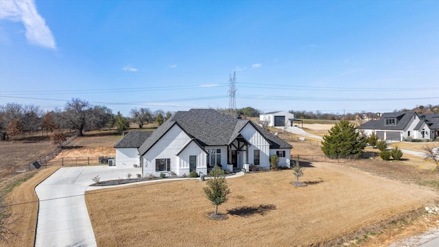 view of front of house with driveway, a shingled roof, a front lawn, and fence