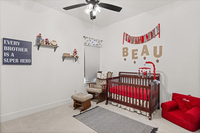 carpeted bedroom featuring a crib and ceiling fan