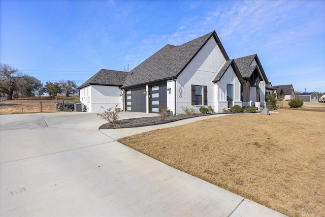 view of front of home featuring an attached garage, central AC, brick siding, driveway, and roof with shingles