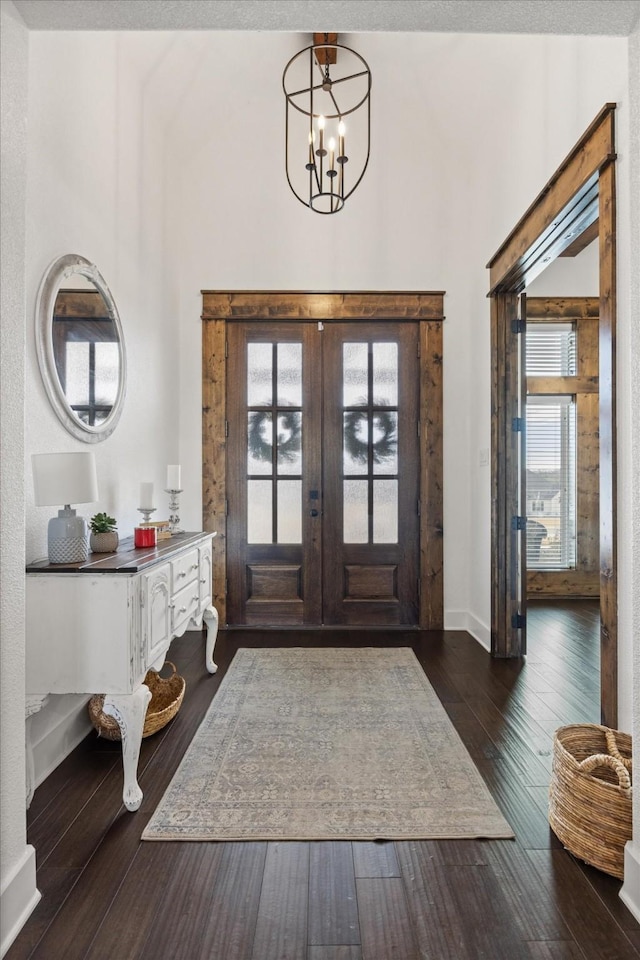 foyer with a chandelier, dark hardwood / wood-style flooring, and french doors