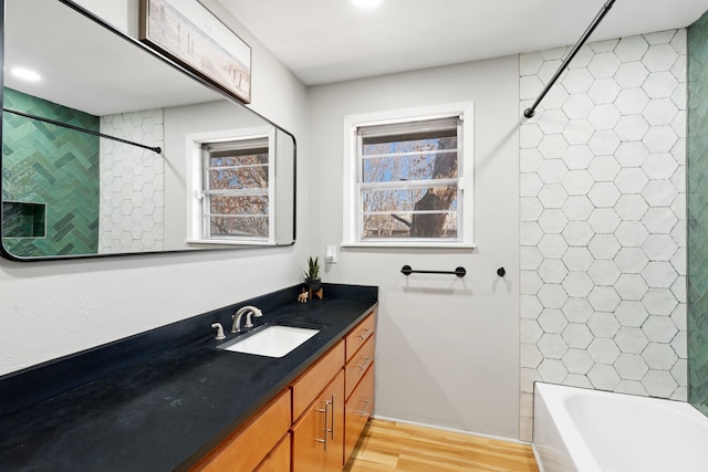 bathroom with hardwood / wood-style floors, vanity, and bathing tub / shower combination