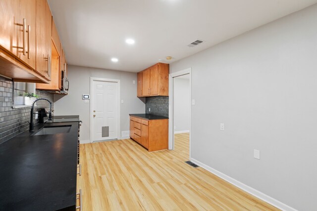 kitchen featuring decorative backsplash, light hardwood / wood-style floors, and sink