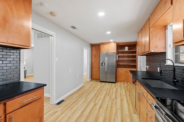 kitchen with decorative backsplash, light wood-type flooring, stainless steel appliances, and sink