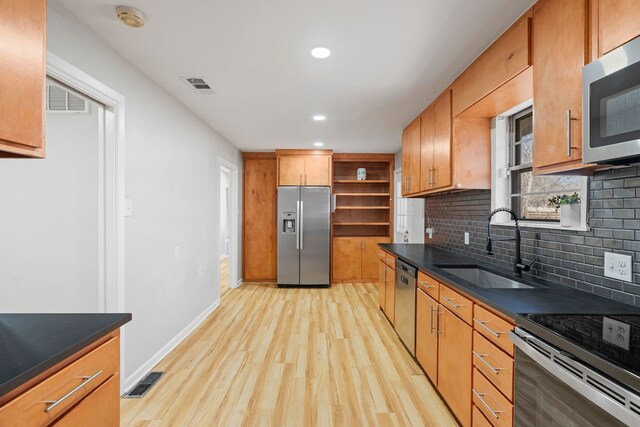 kitchen with backsplash, light wood-type flooring, sink, and appliances with stainless steel finishes