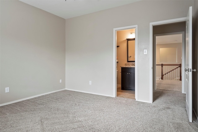 unfurnished bedroom with connected bathroom and light colored carpet