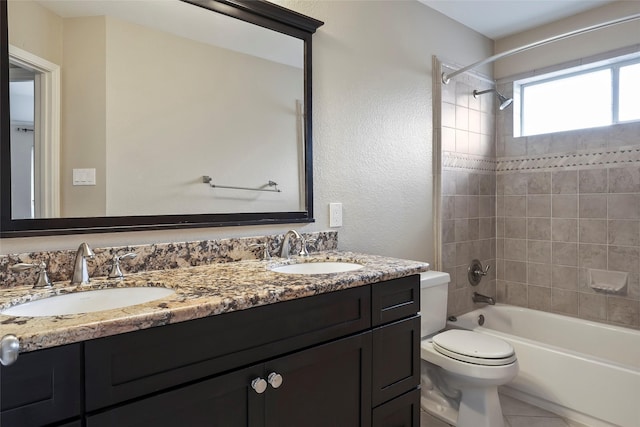 full bathroom with tile patterned flooring, vanity, tiled shower / bath combo, and toilet