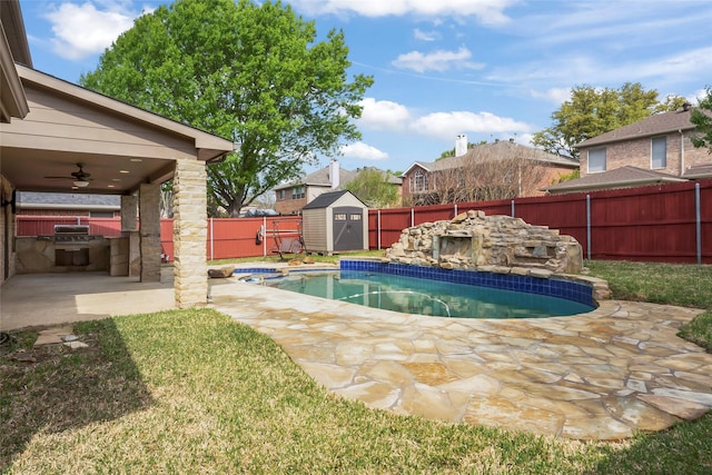 view of pool featuring an outdoor kitchen, ceiling fan, a patio, and a shed