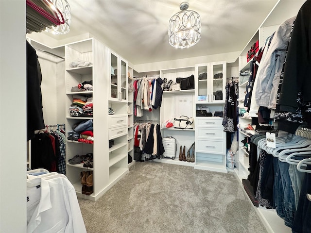 walk in closet featuring light carpet and an inviting chandelier