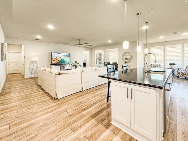 1133 Cornerstone Dr, Little Elm, TX 76227 - kitchen with dark countertops, a sink, open floor plan, light wood-style flooring, and ceiling fan
