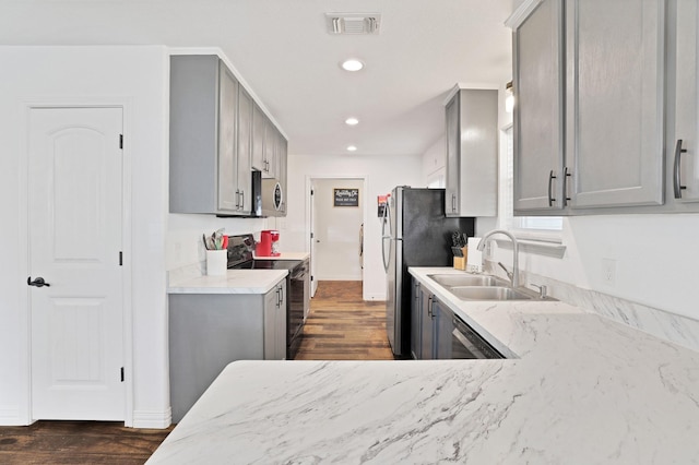 kitchen with gray cabinets, sink, light stone countertops, and stainless steel appliances