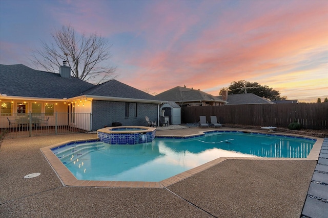 pool at dusk featuring a diving board, an in ground hot tub, and a patio