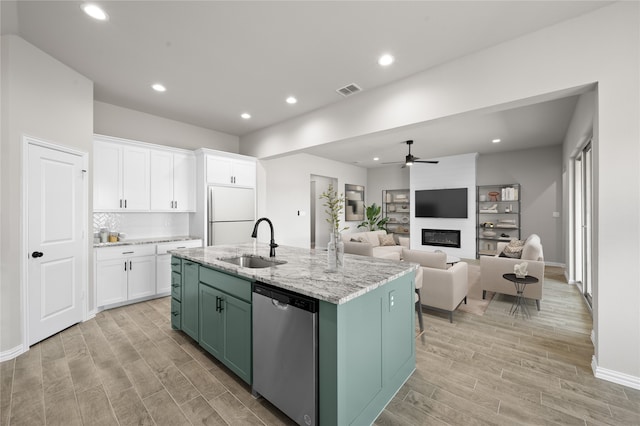 707 Shadle Rd, Poolville, TX 76487 - kitchen with stainless steel dishwasher, a sink, white fridge, a fireplace, and a ceiling fan