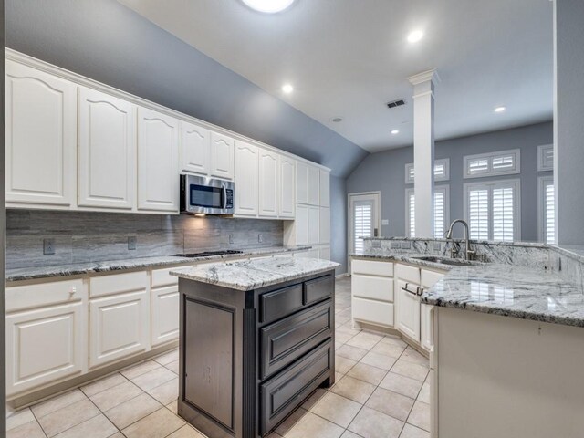 kitchen featuring appliances with stainless steel finishes, backsplash, sink, a center island, and white cabinetry