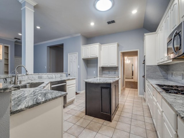 kitchen featuring sink, ornate columns, appliances with stainless steel finishes, light stone counters, and white cabinetry