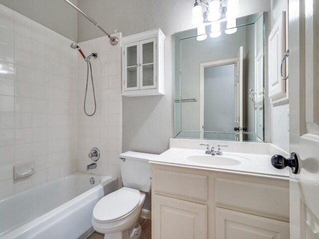 full bathroom featuring tiled shower / bath combo, toilet, and vanity