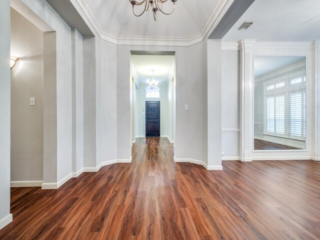 hall with dark wood-type flooring, an inviting chandelier, plenty of natural light, and ornamental molding