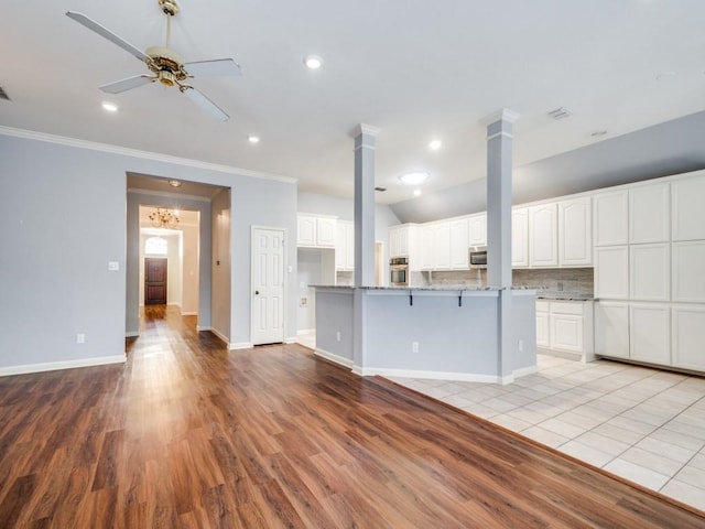 unfurnished living room featuring light hardwood / wood-style flooring, ceiling fan, crown molding, and ornate columns