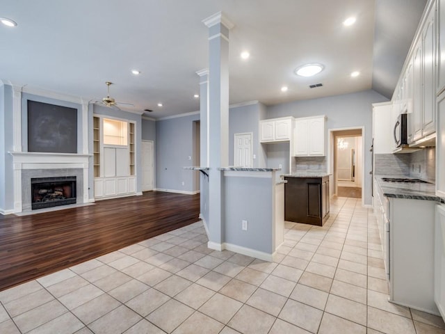 kitchen with backsplash, a center island, white cabinets, and light tile patterned floors