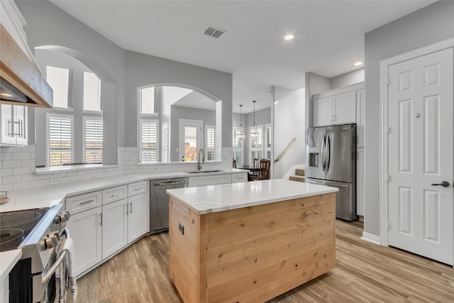 kitchen featuring premium range hood, white cabinetry, a center island, and appliances with stainless steel finishes