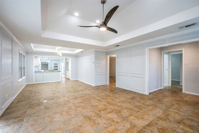 interior space with ceiling fan with notable chandelier, ornamental molding, and a raised ceiling