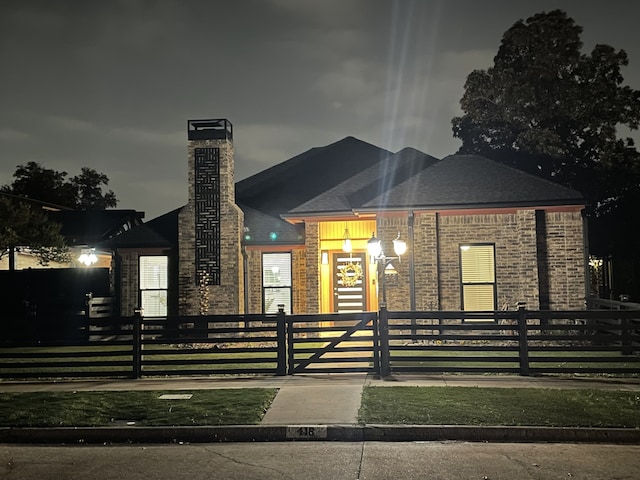 view of front of home with a fenced front yard, brick siding, and a chimney