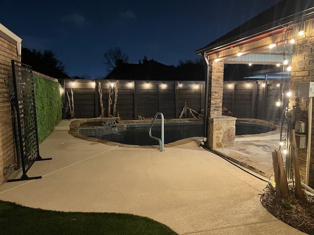 patio at night featuring a fenced in pool